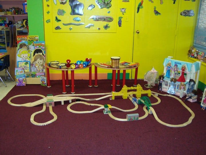 Toy train track on a carpeted floor in a room with yellow walls
