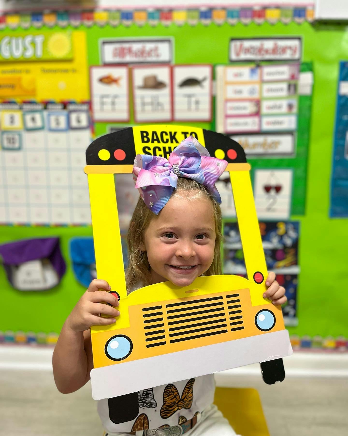 Child holding a school bus cutout with "BACK TO SCHOOL" text