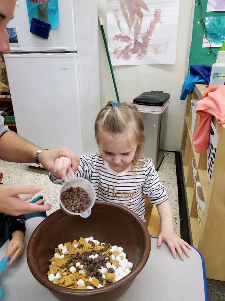 Person and child adding ingredients to a bowl