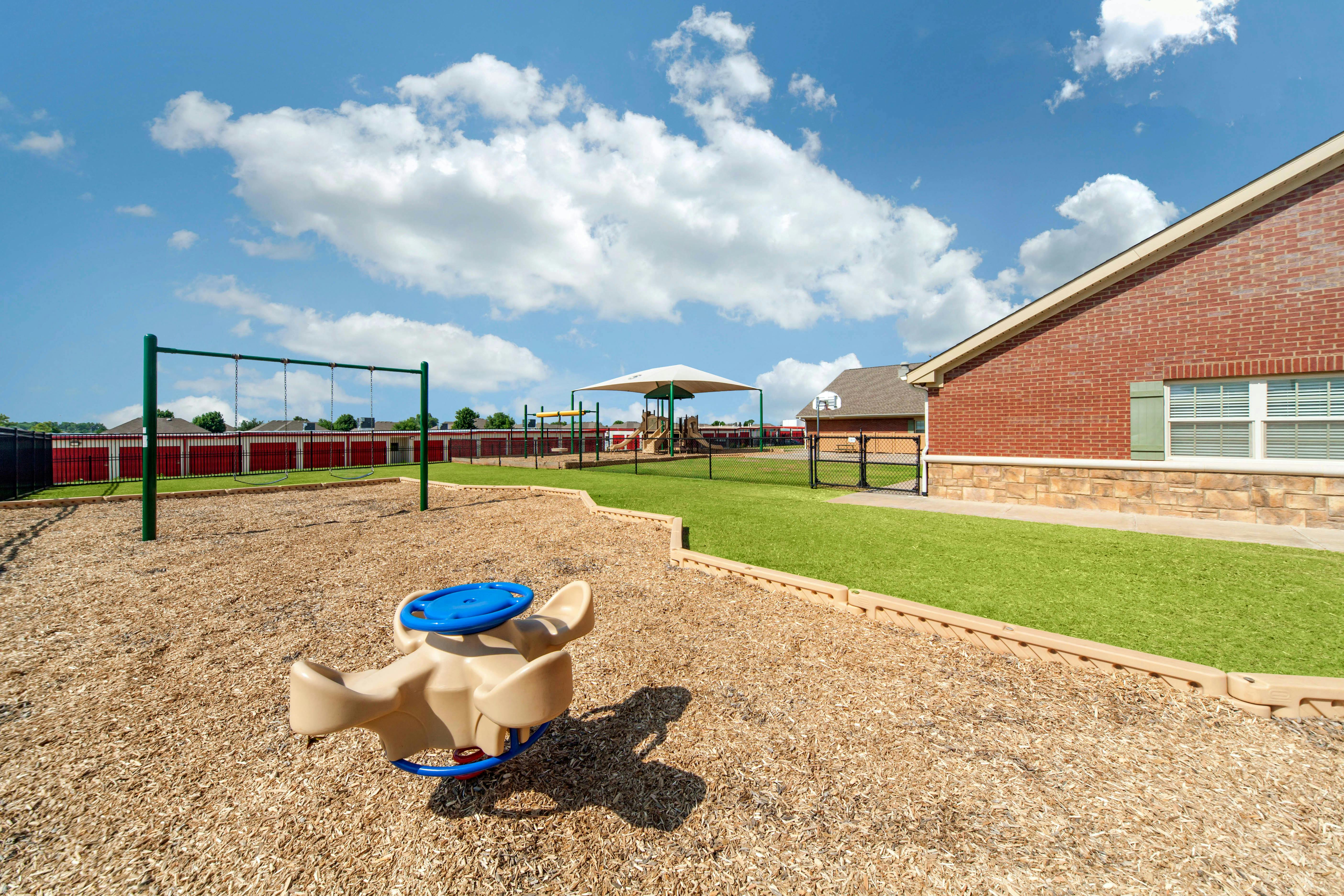 Playground with swings, seesaw, covered play structure, and building