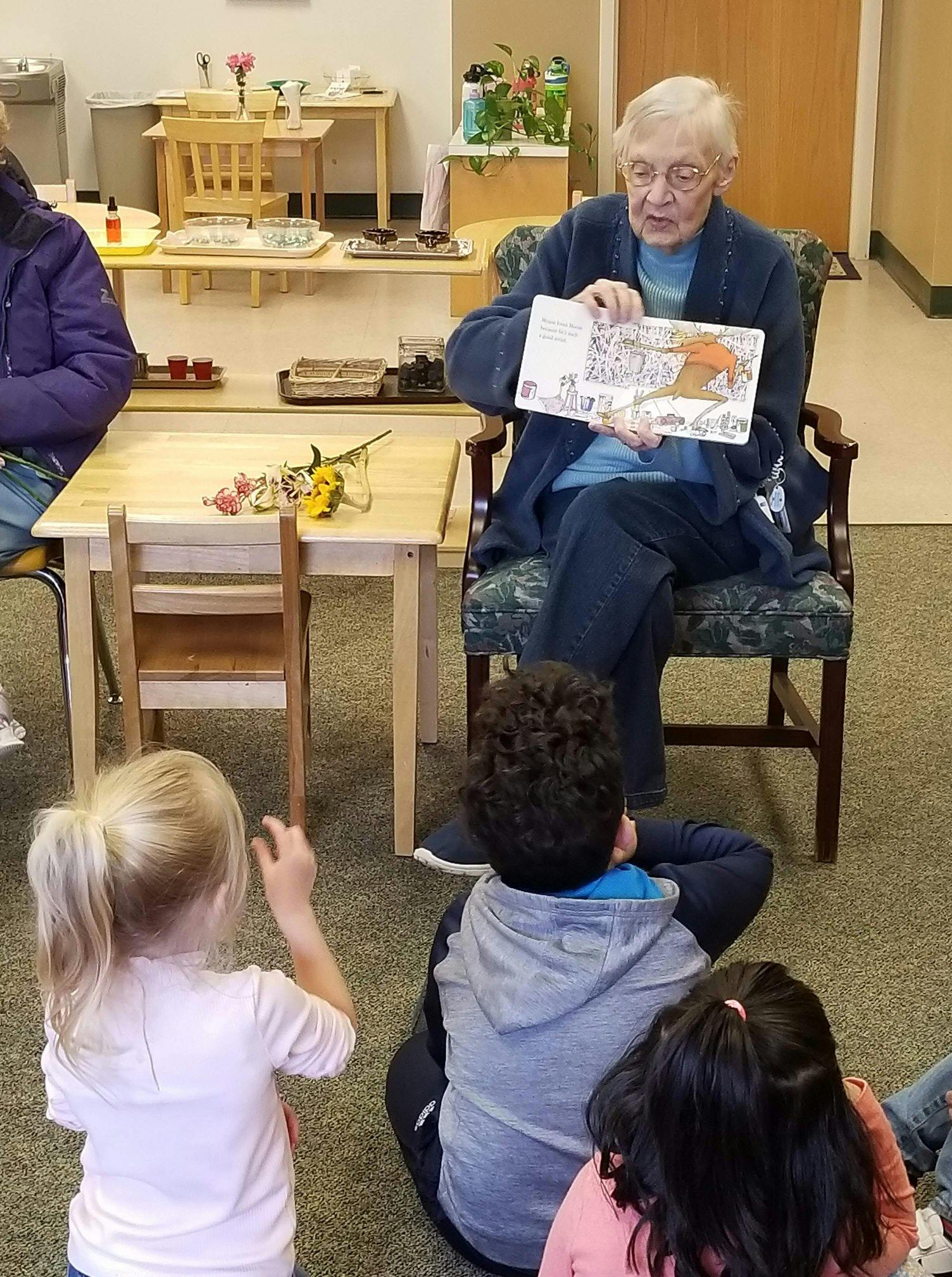 Person reading a book to children sitting on the floor