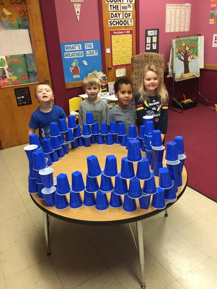 Four children standing behind a table with blue cups stacked in a circle