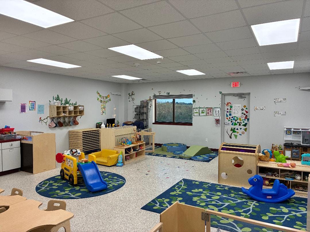 Empty classroom with play mats, small tables, and toys