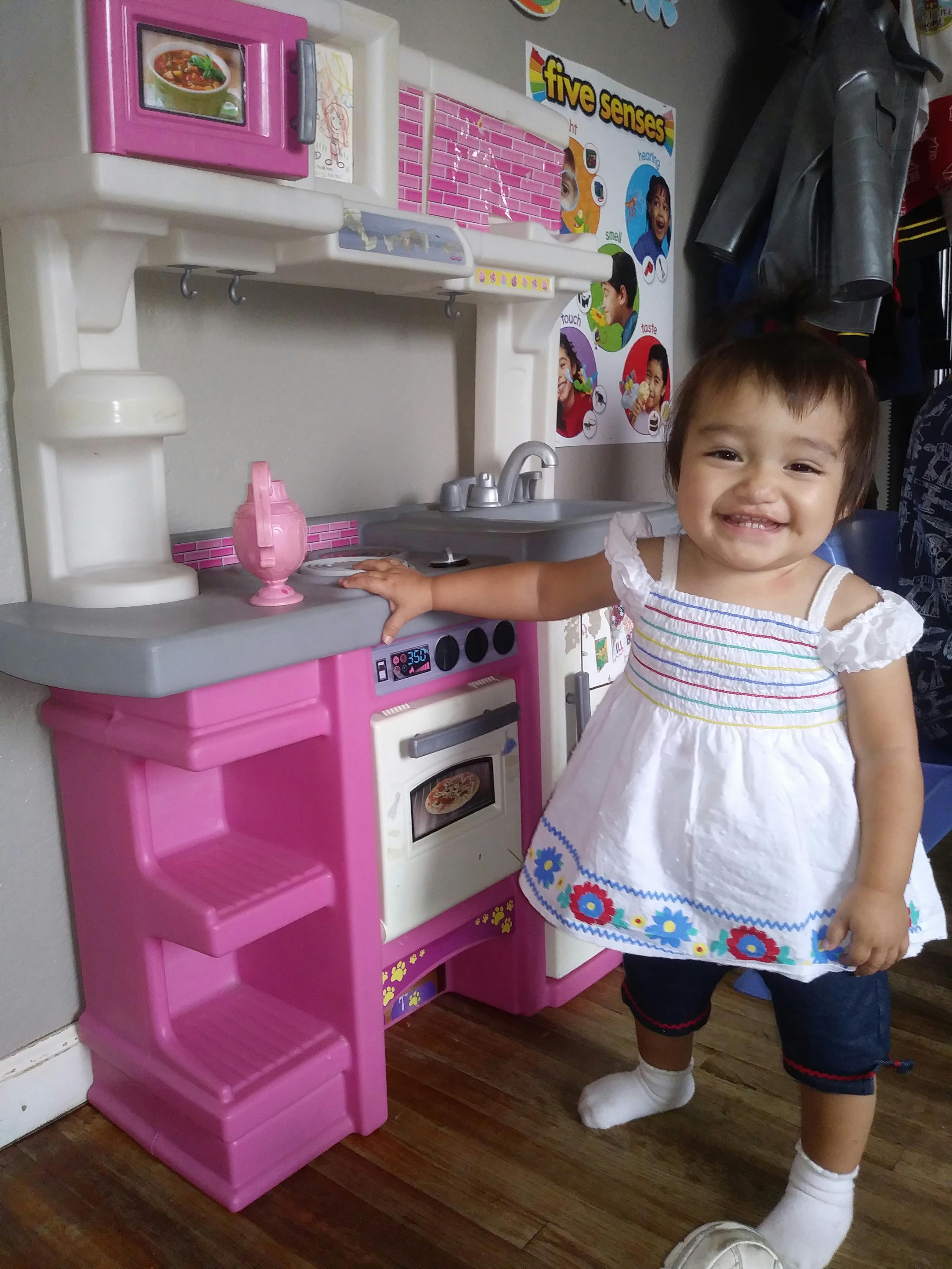Child standing next to a toy kitchen set