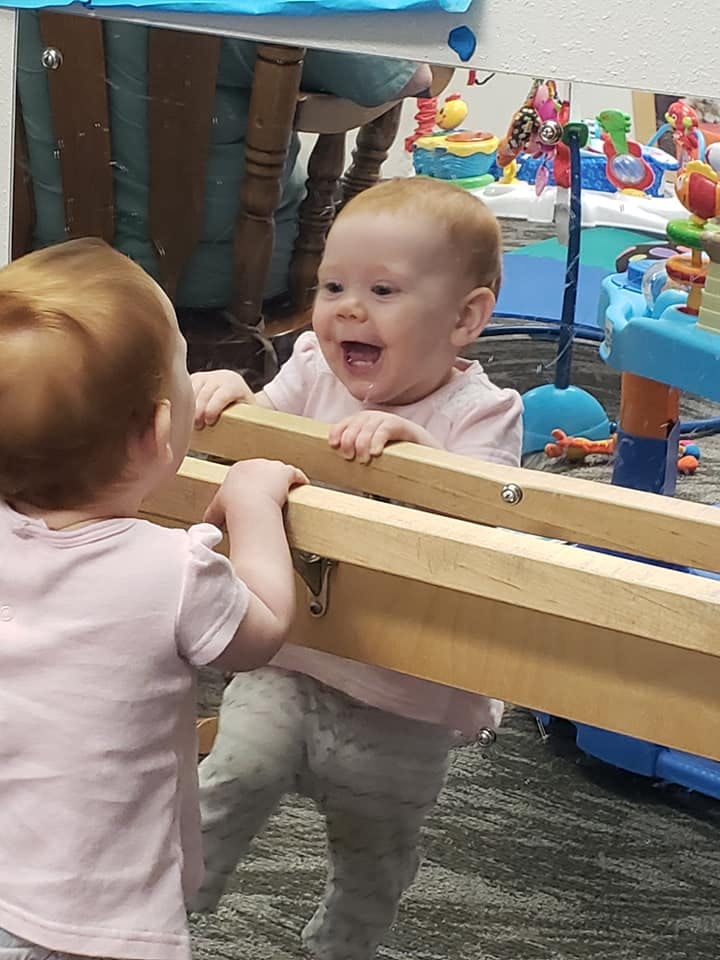 Two children standing at a wooden barrier, one looking at the other