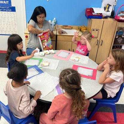 Adult and children sitting around a table in a classroom