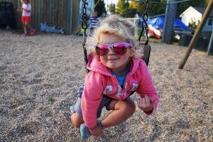 Child in sunglasses on a swing