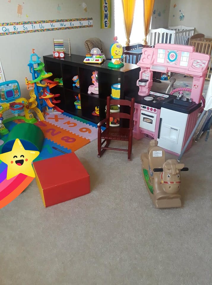 Playroom with toys, including a play kitchen, rocking horse, and alphabet mat