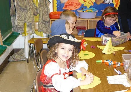 Child in pirate costume smiling at a table with other children