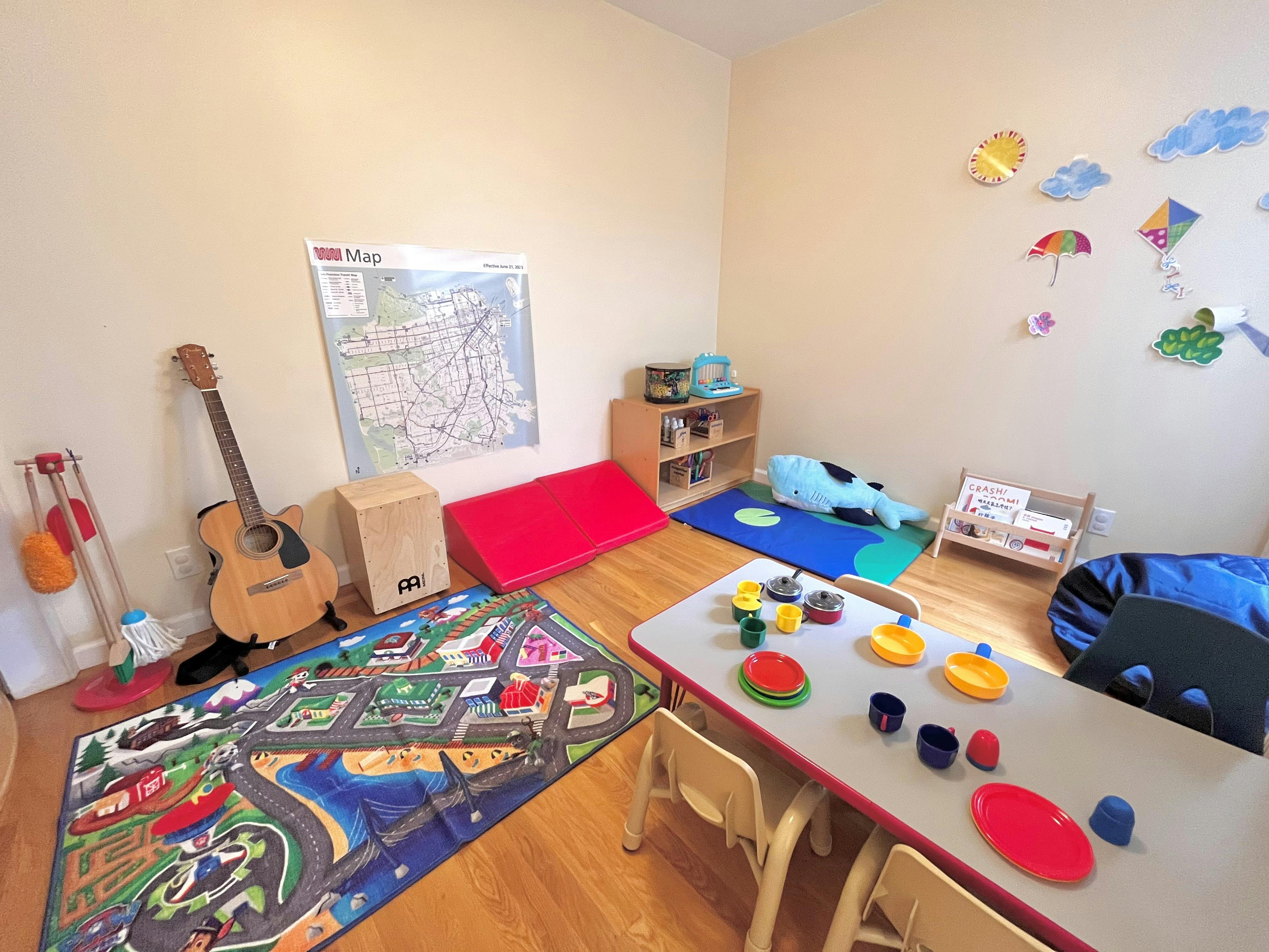 Playroom with a child-sized table, play rugs, toys, and musical instruments