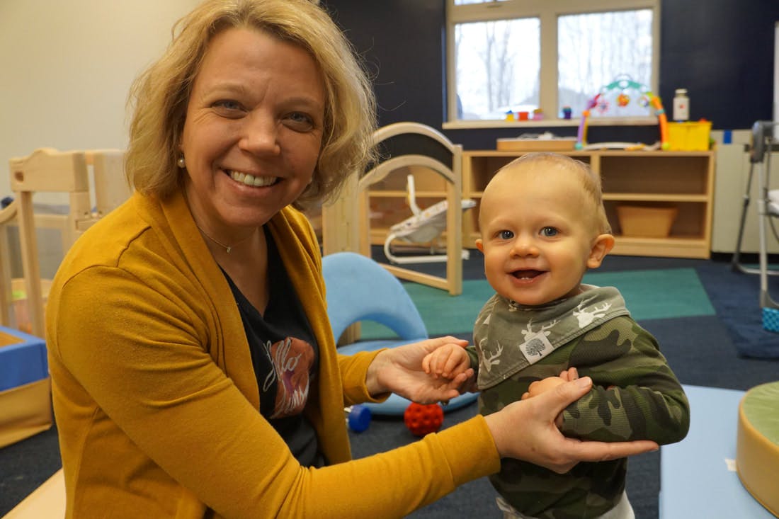 Person holding a child's hands in a classroom