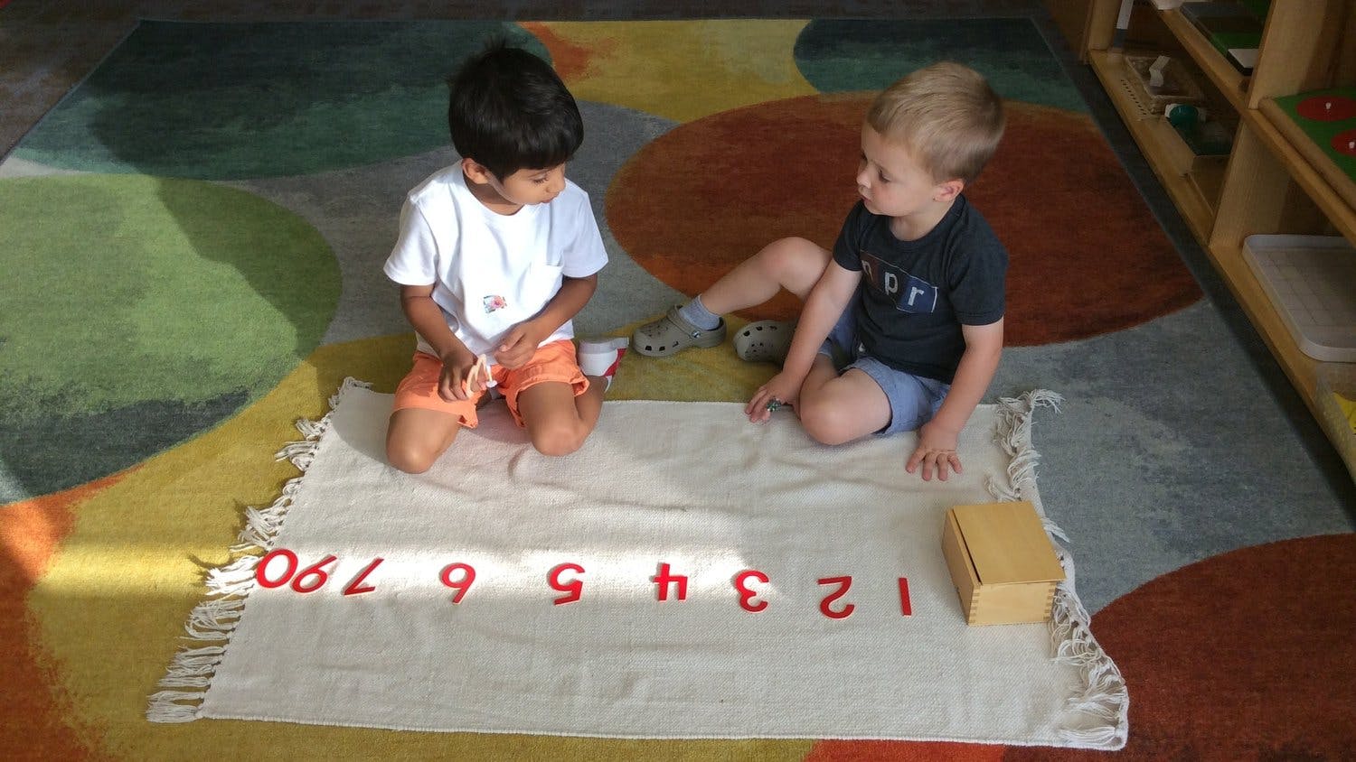 Two children on a rug with number blocks