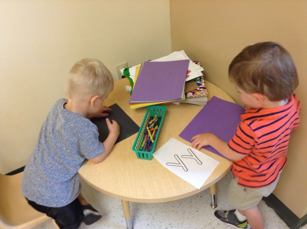 Two children drawing at a small round table