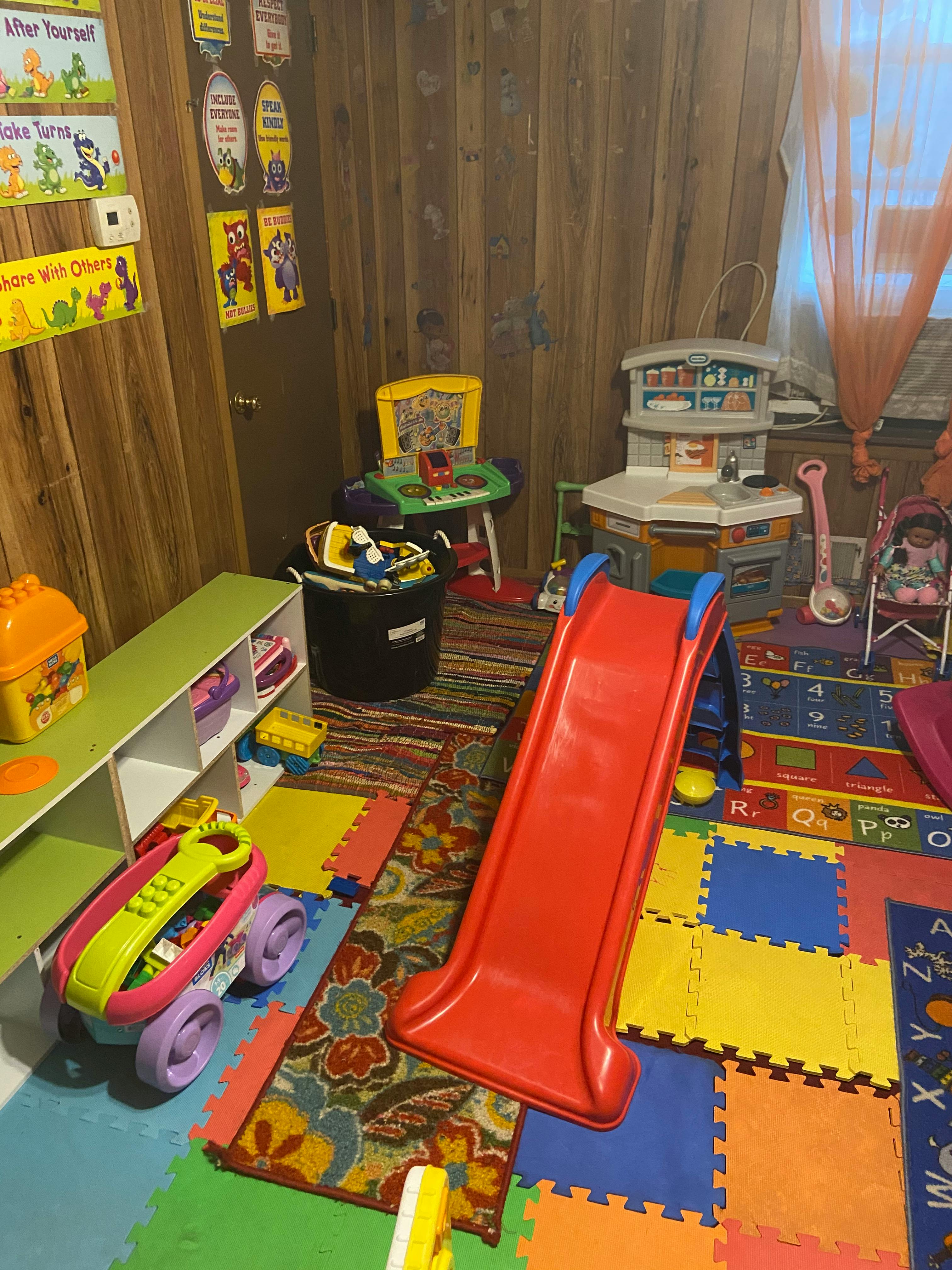Playroom with a red slide, toy kitchen, and colorful floor mats