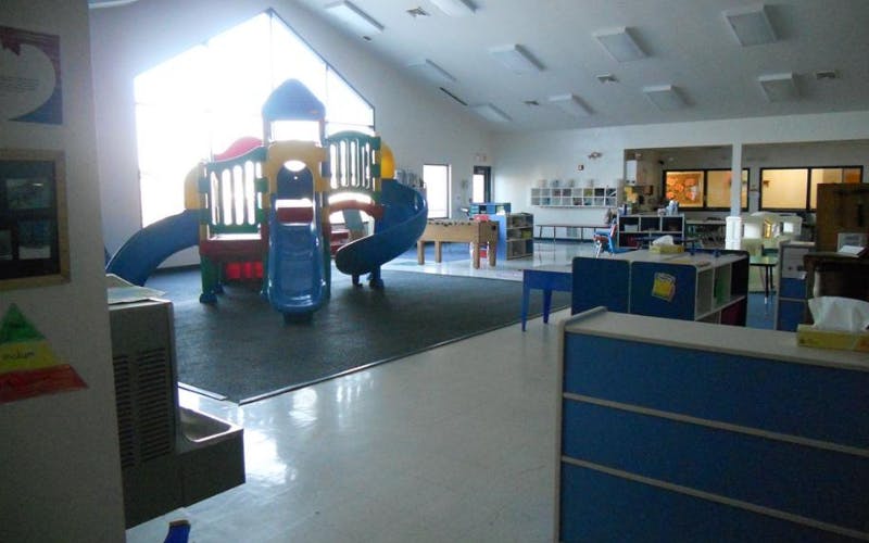 Indoor playground with a colorful play structure and slide in a classroom