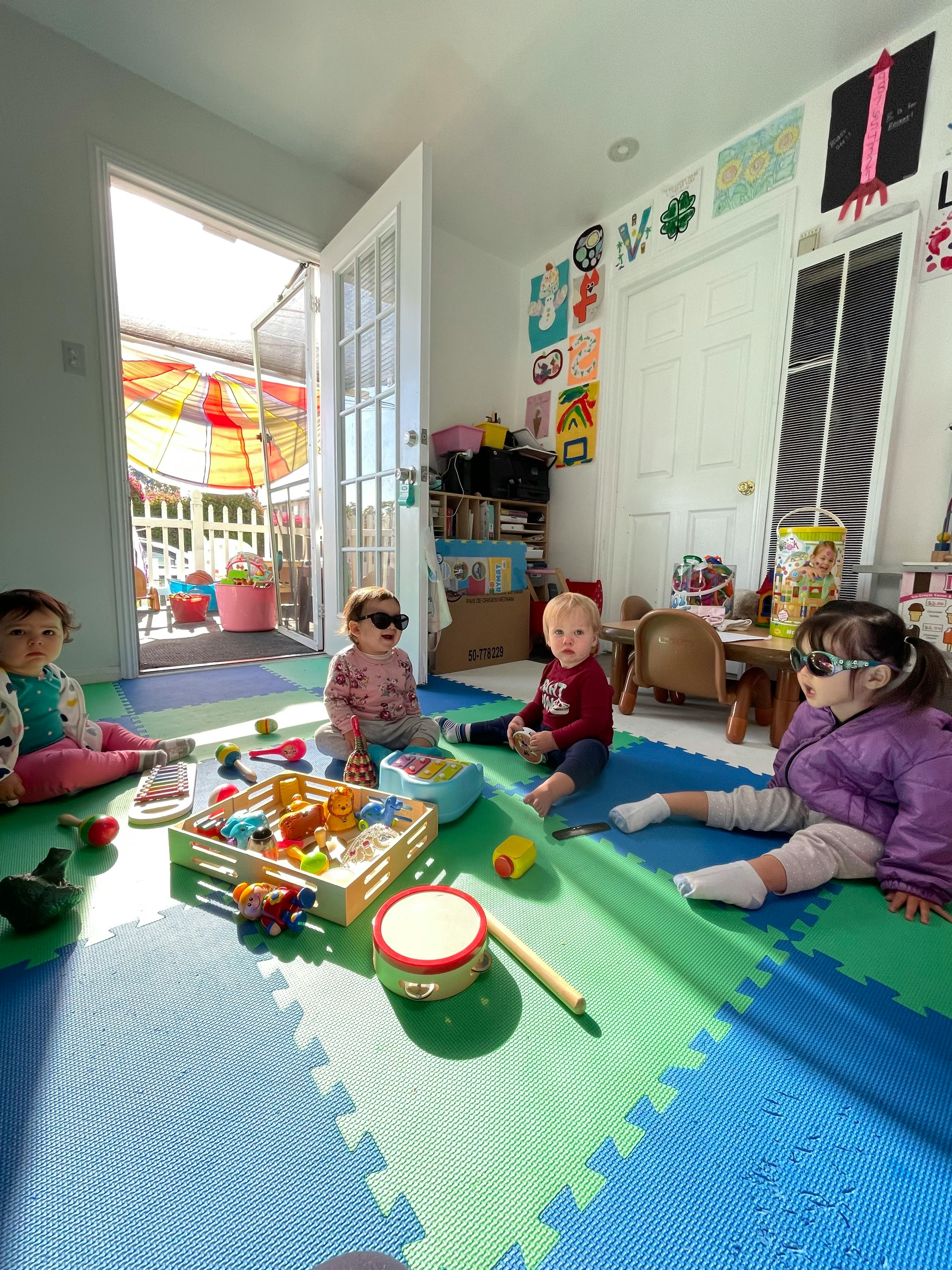 Four children playing with toys on a colorful mat indoors
