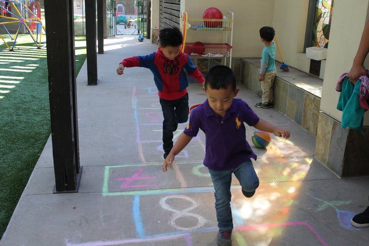 Two children playing hopscotch on a sidewalk