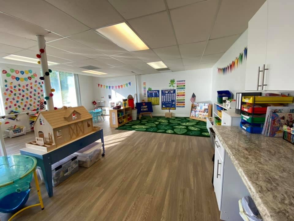 Classroom with a dollhouse, green rug, and colorful decorations