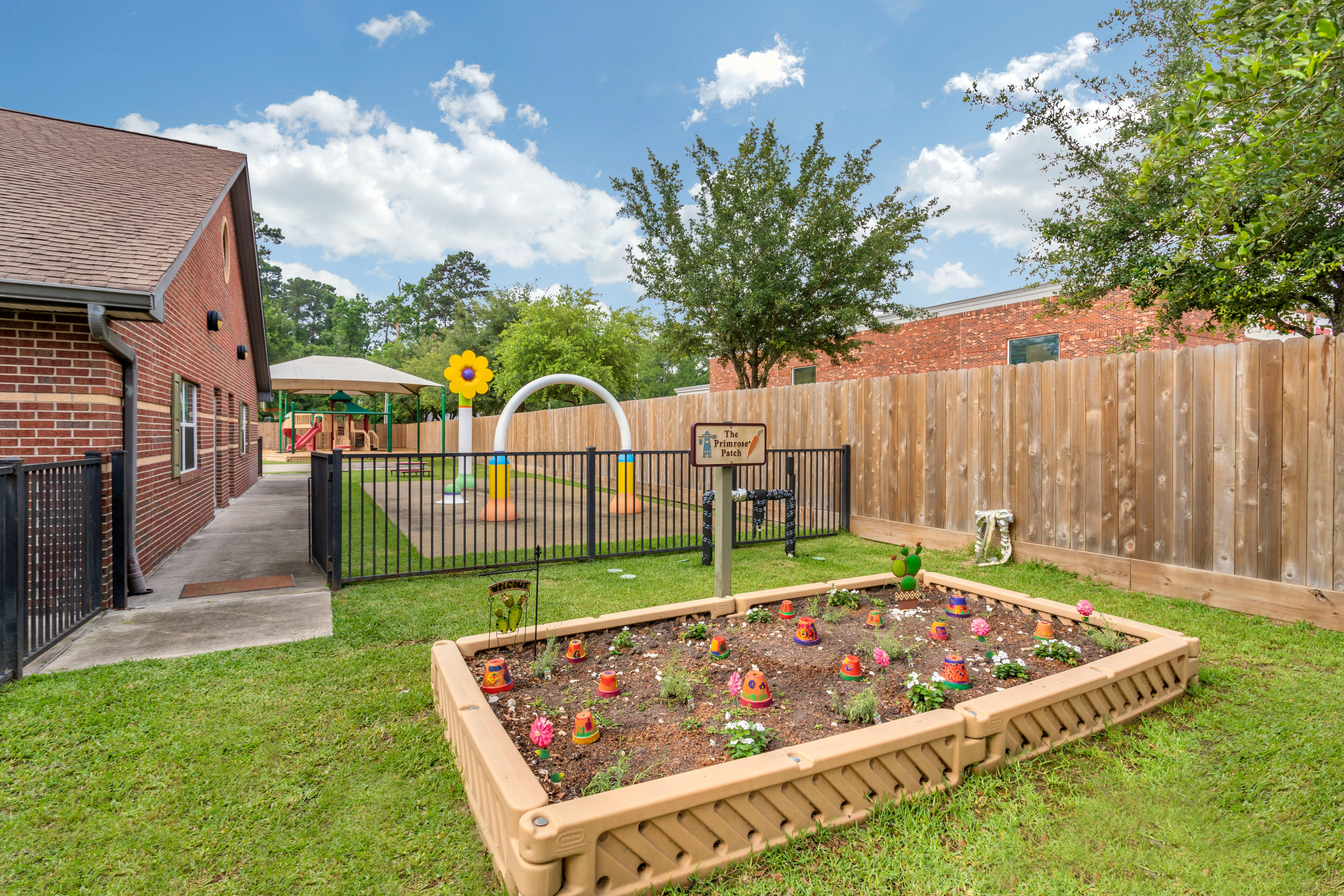 A children's playground area with a colorful flower sprinkler and a garden bed