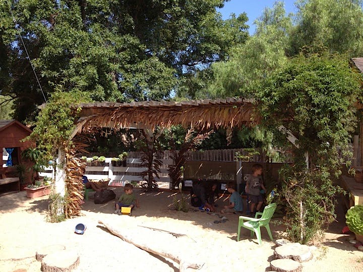 Outdoor area with a thatched roof structure and sandy ground
