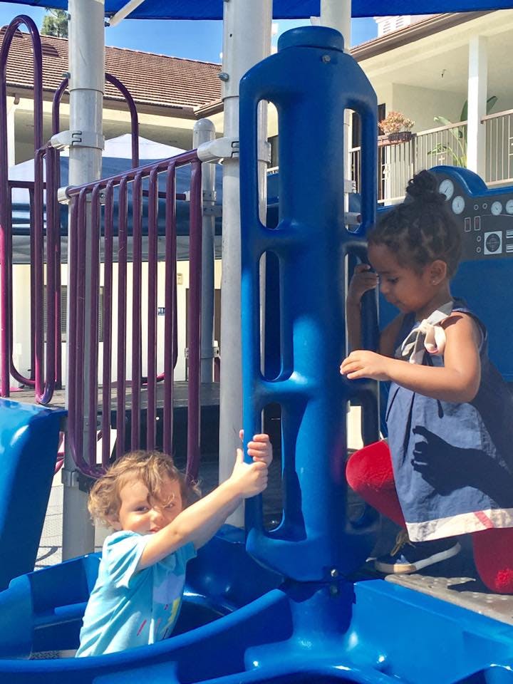 Two children playing on blue playground equipment