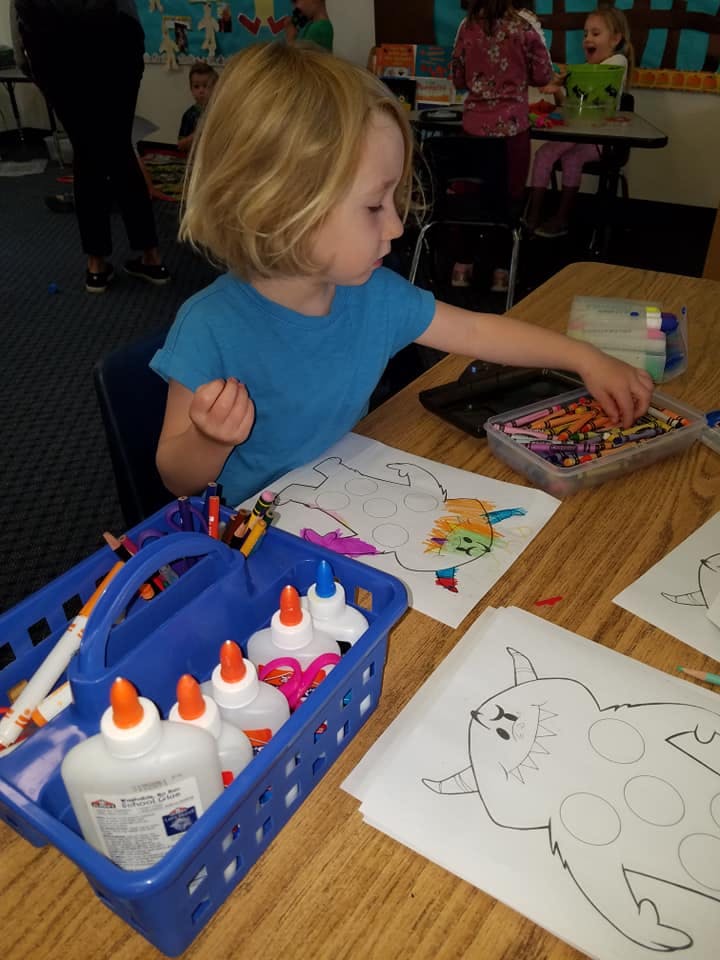 Child coloring at a table with art supplies