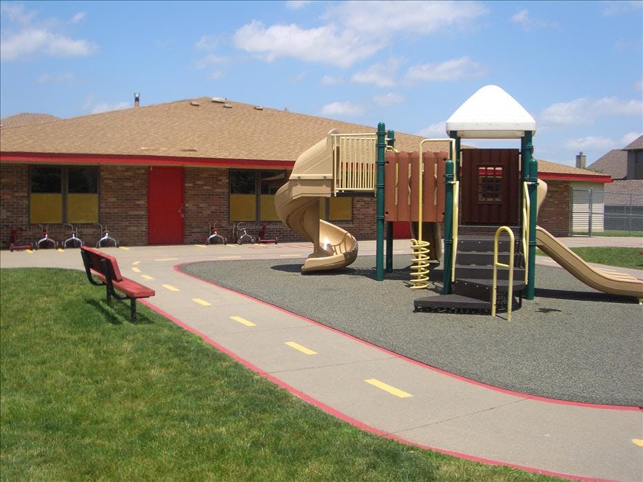 Playground with slides, a spiral slide, and steps next to a brick building