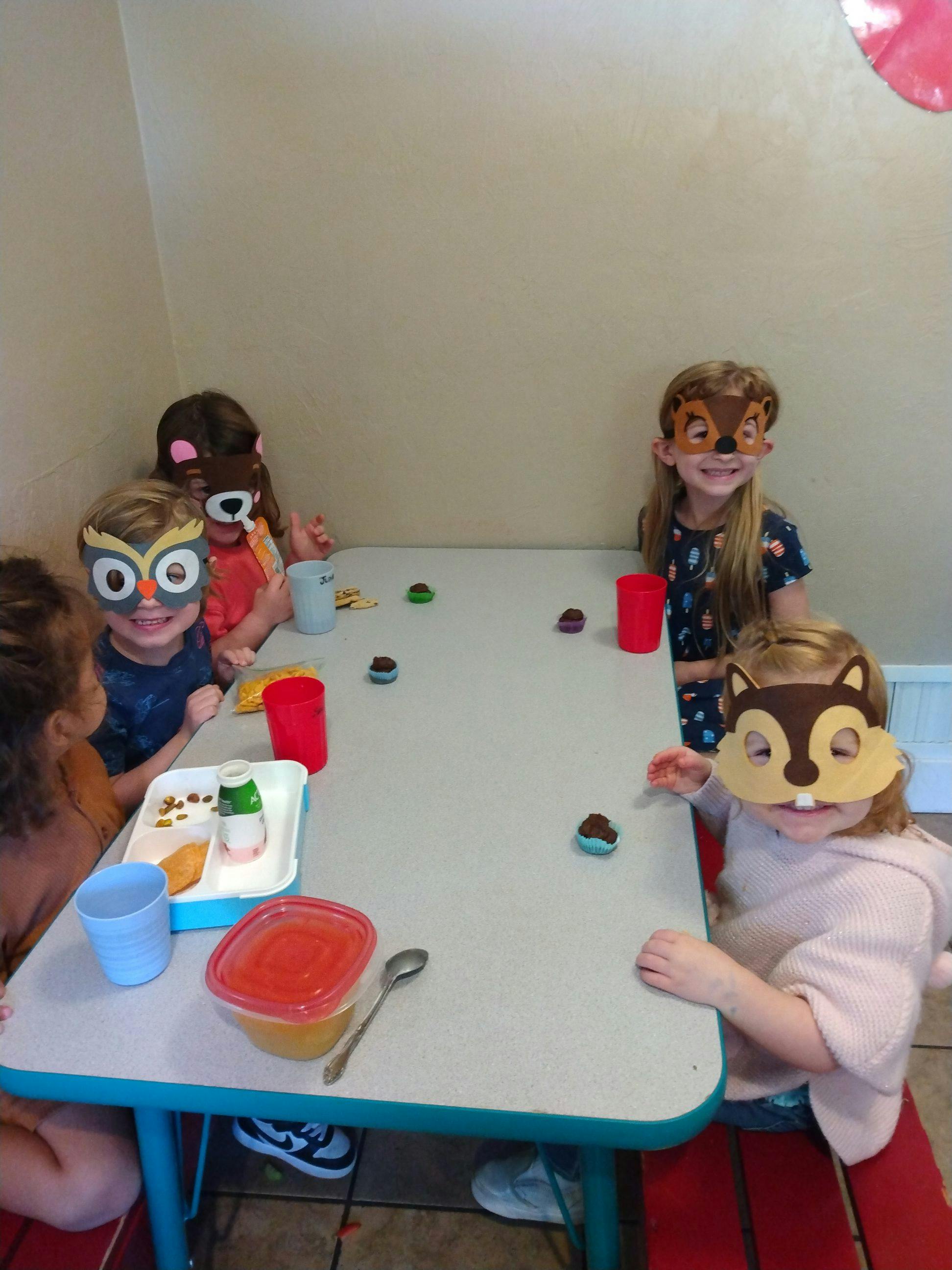 Children wearing animal masks sitting at a table