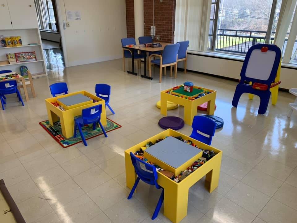 Empty classroom with small yellow tables and blue chairs