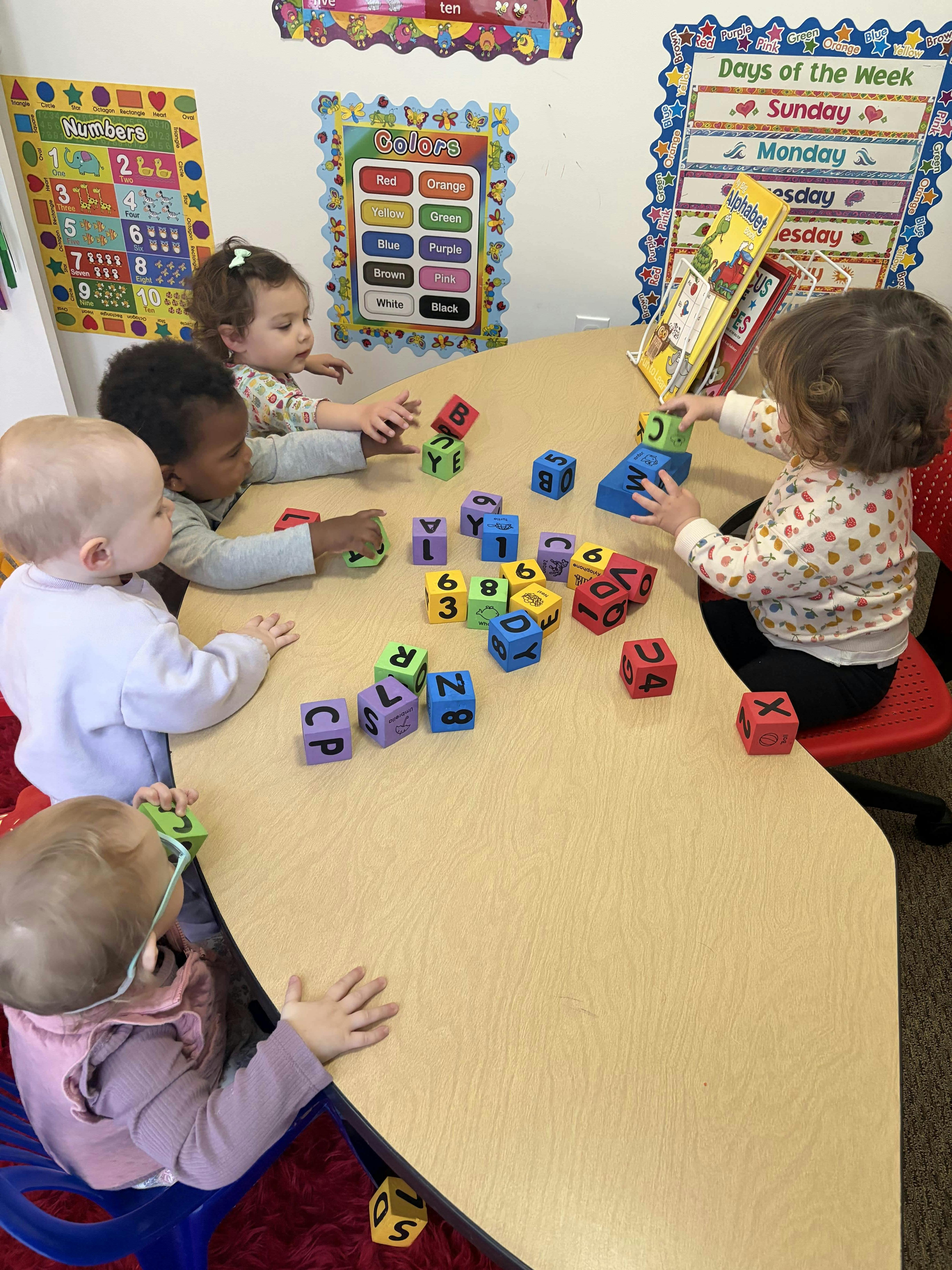 Group of children playing with educational letter and number blocks at a table