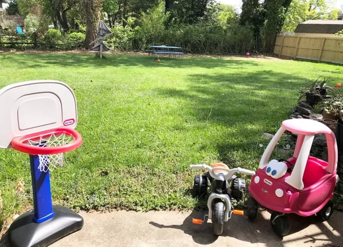 Toy basketball hoop, toy motorcycle, and toy car in a grassy yard