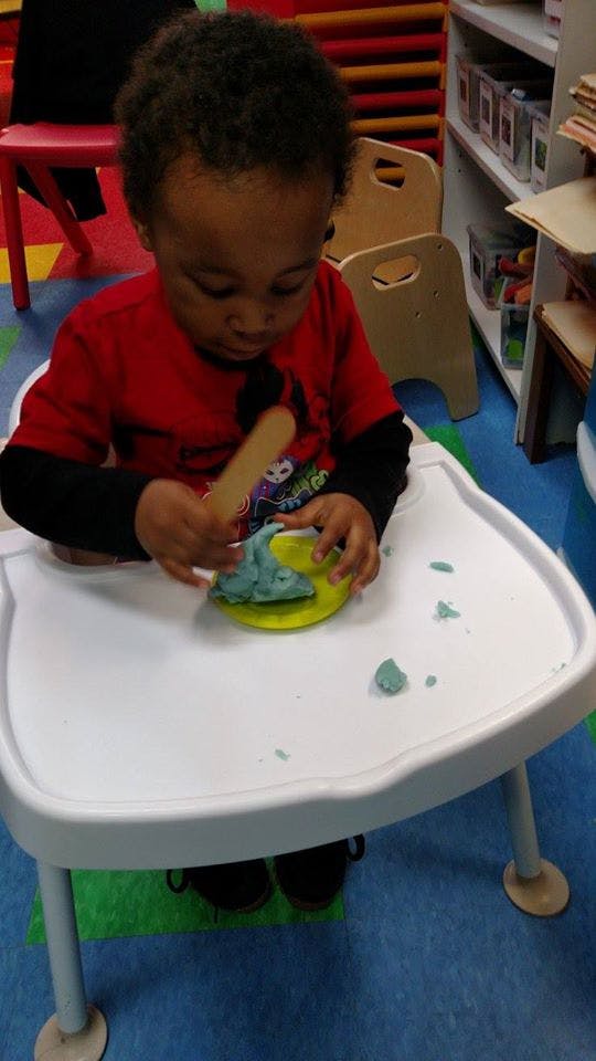 Child playing with modeling clay at a table