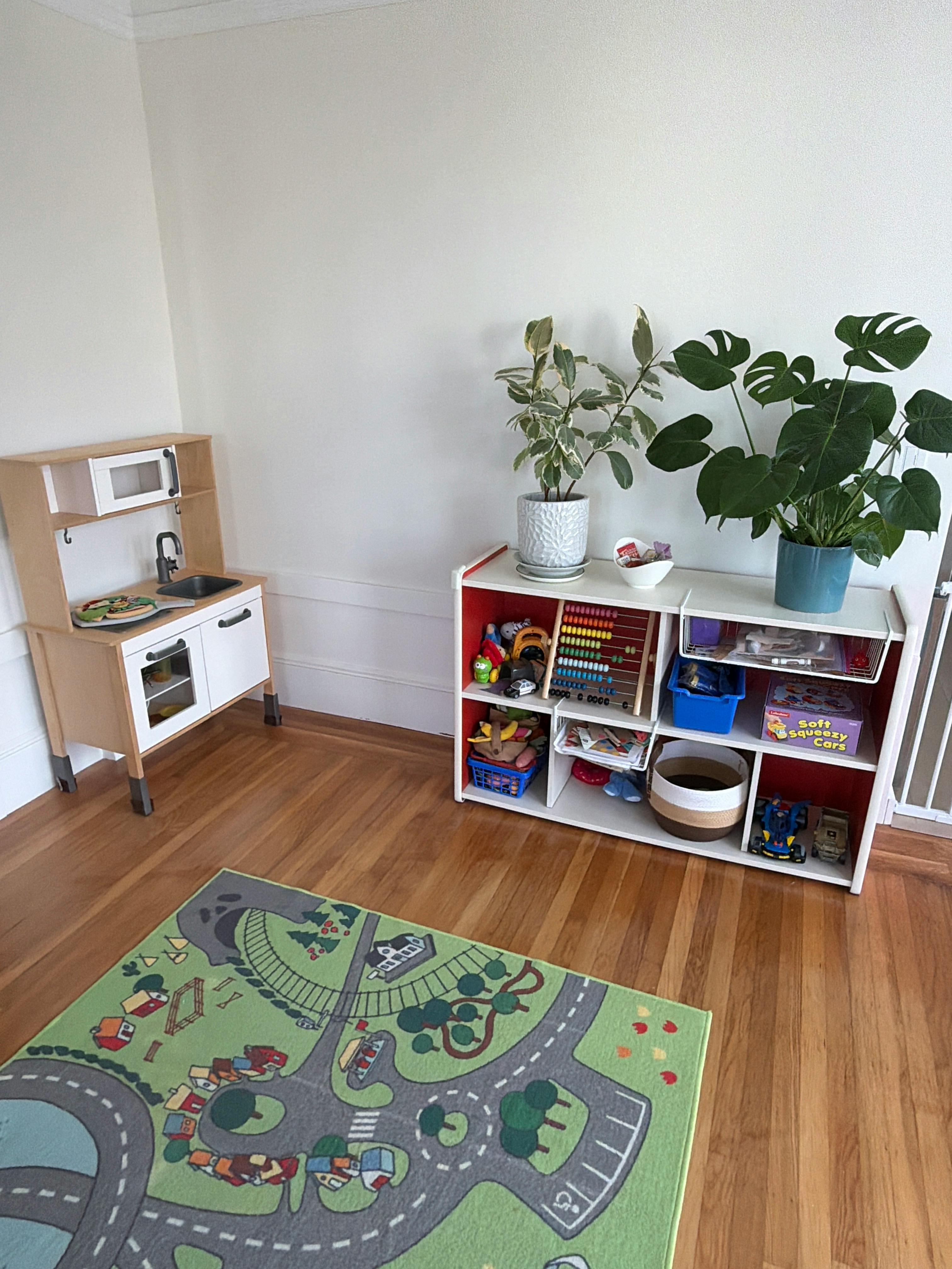 Toy storage shelf and play kitchen on a road pattern rug