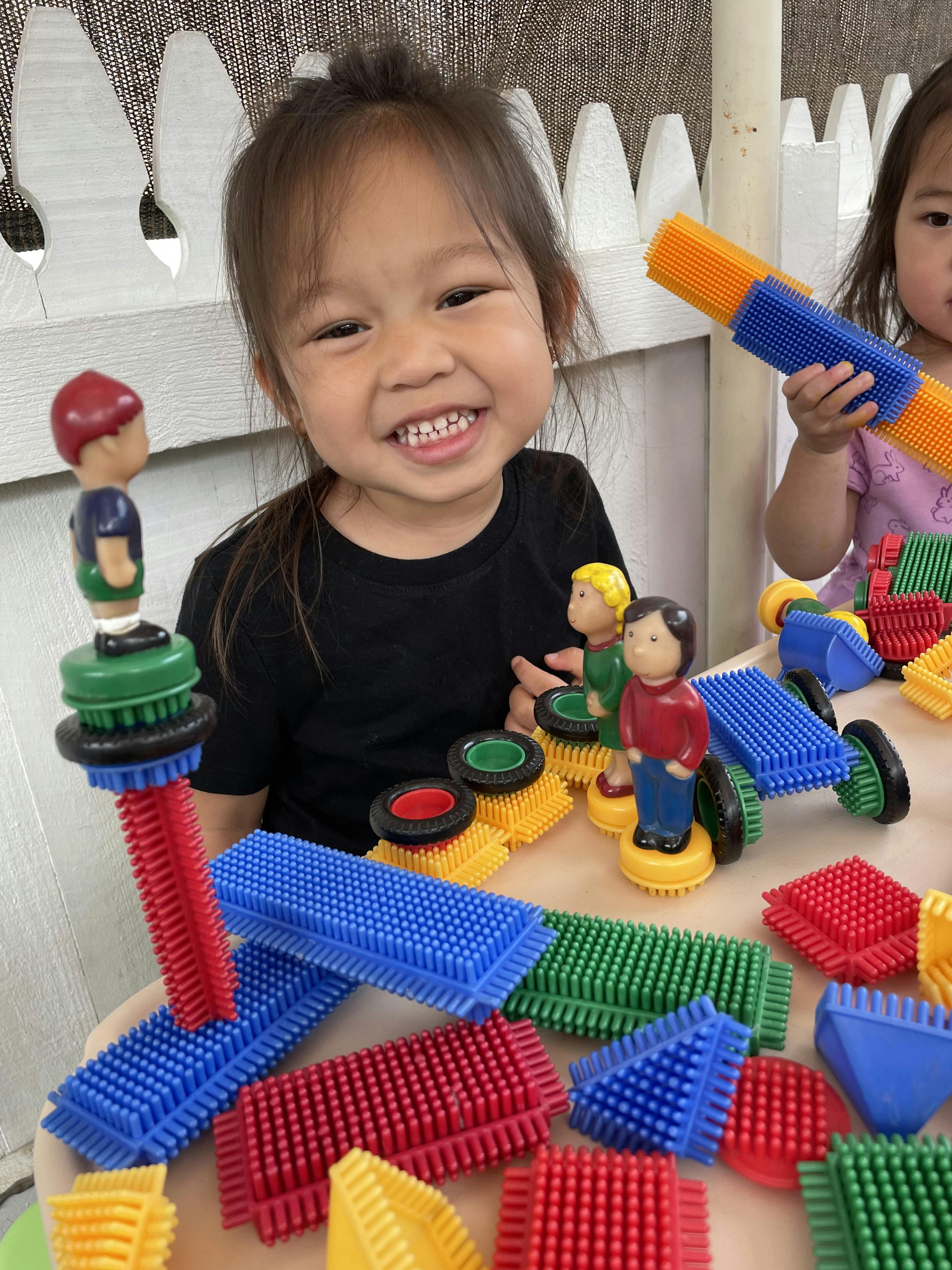 Child smiling while playing with colorful interlocking building toys