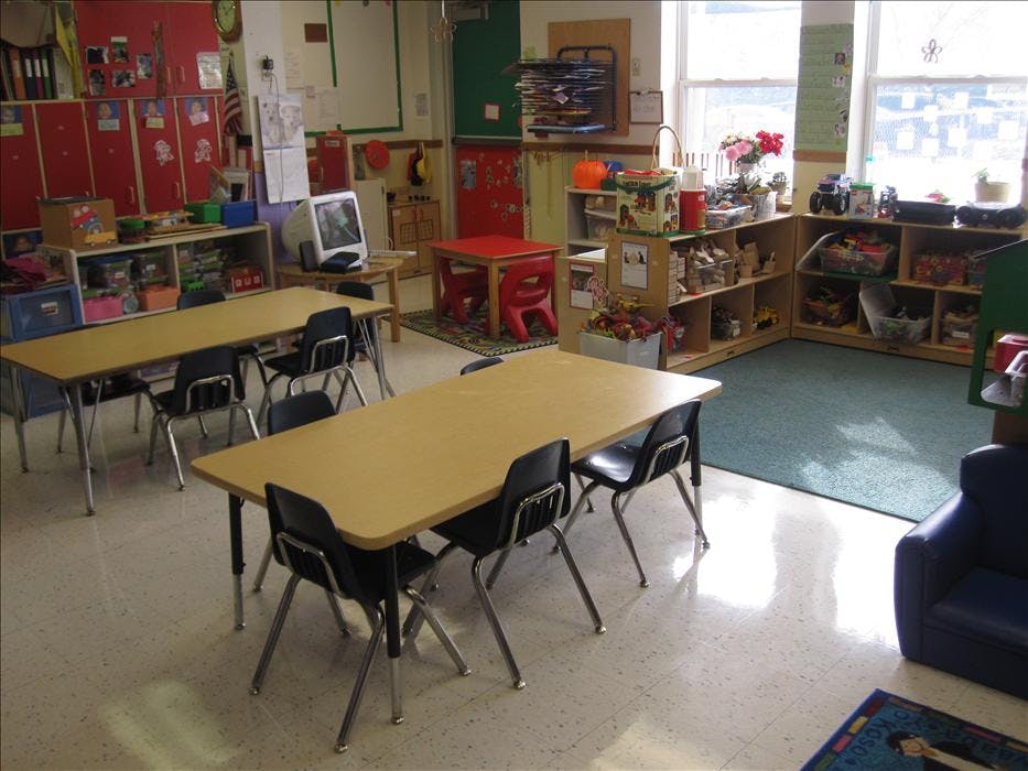 Classroom with child-sized tables, chairs, and shelving units