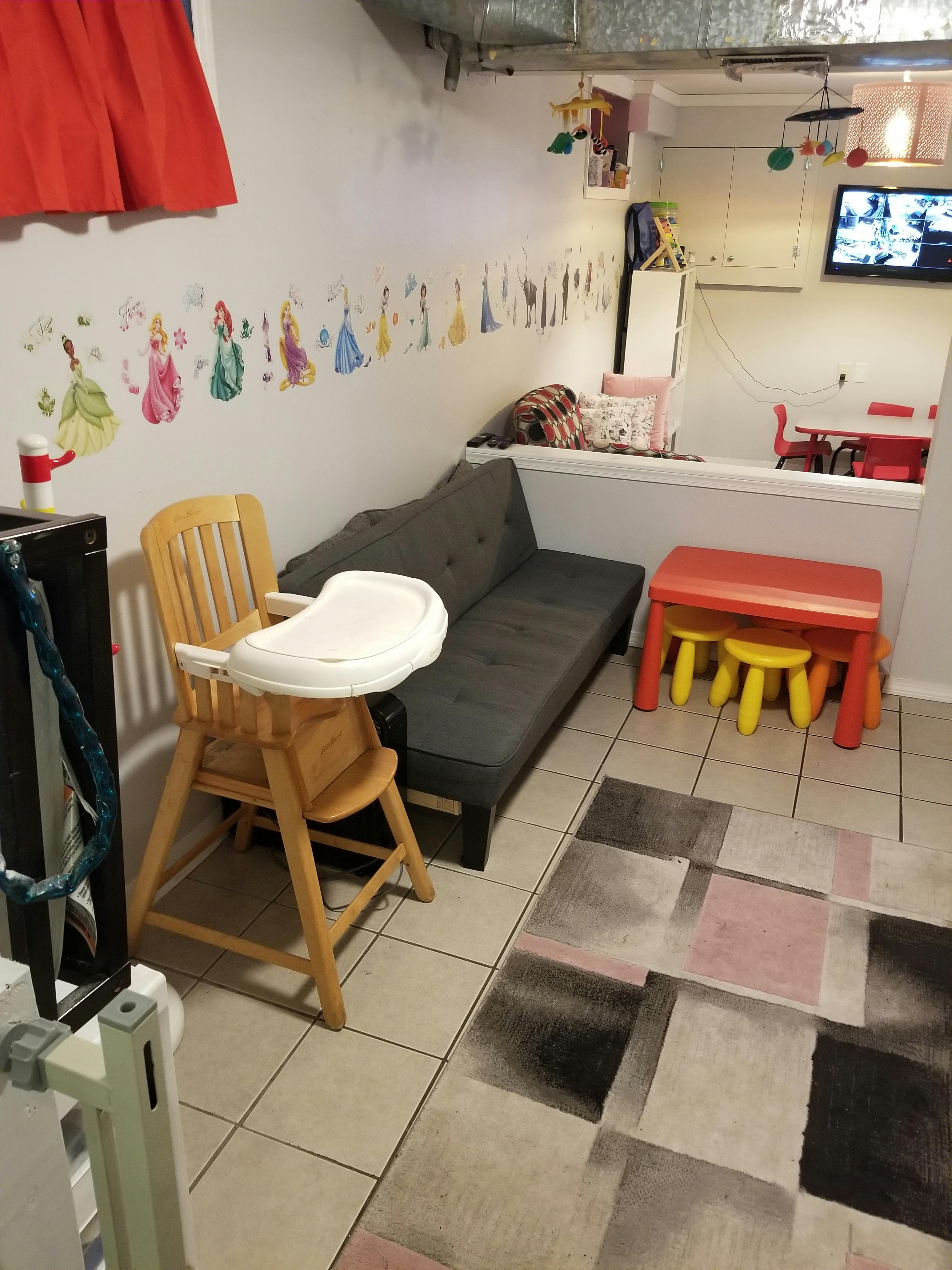 High chair next to a futon and a small red table with yellow stools