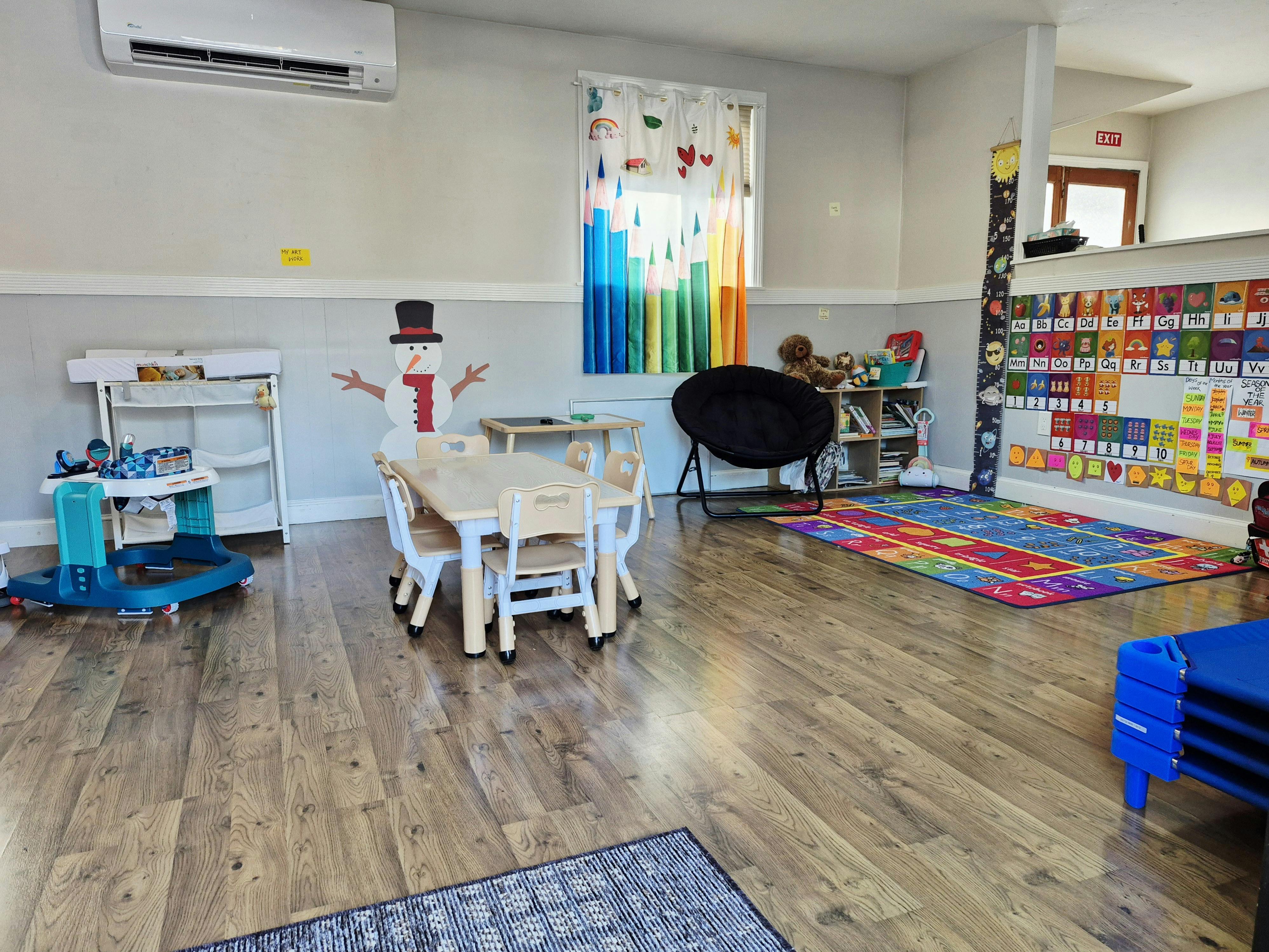 Playroom with small tables and chairs, a colorful rug, and a snowman decoration