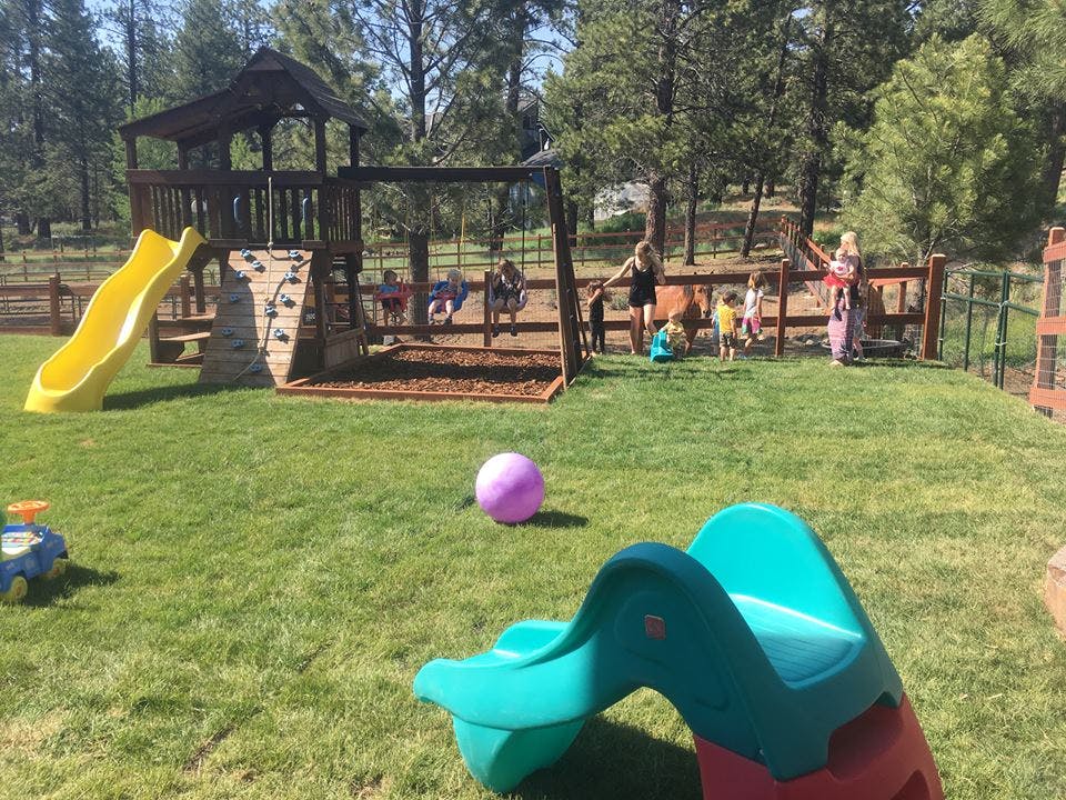 Playground with a wooden playset, yellow slide, and children playing