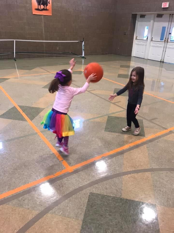 Two children playing with a ball in a gym