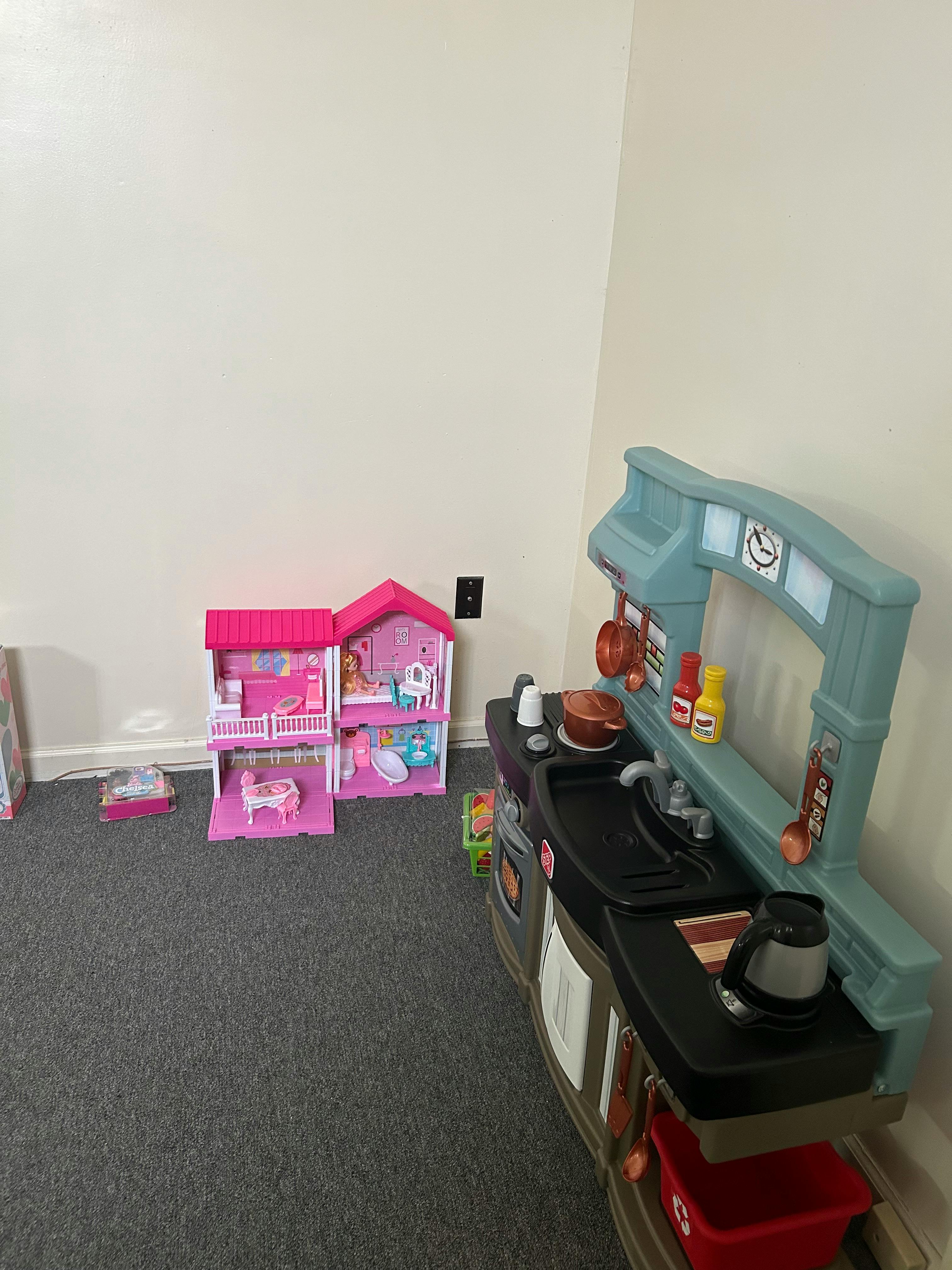 Toy kitchen and dollhouse in a room