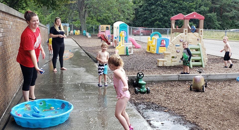 Adults and children playing with water in a shallow pool on a playground