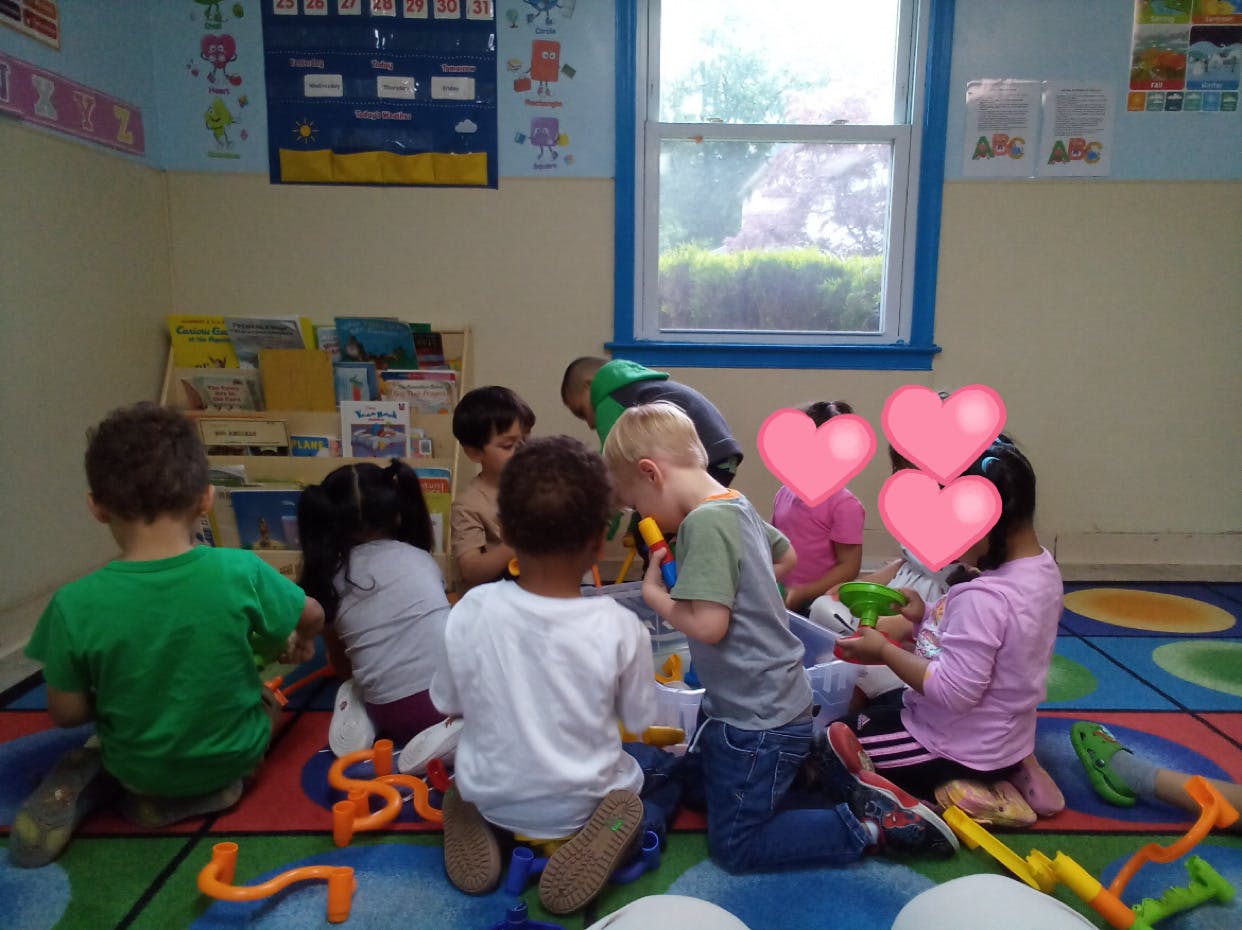 Children playing with toys on a colorful rug in a classroom