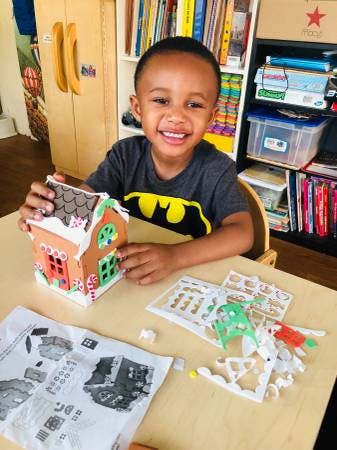 Child assembling a gingerbread house at a table