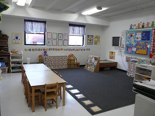Empty classroom with tables, chairs, and learning materials