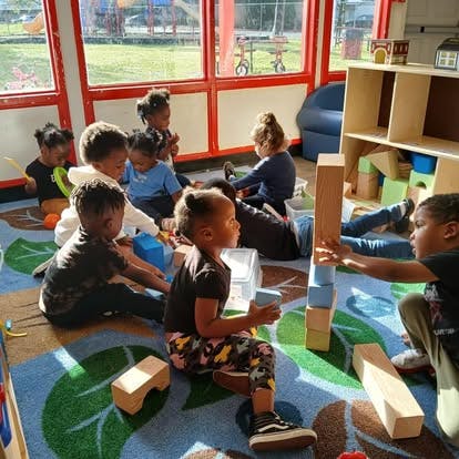 Children playing with blocks on a colorful rug in a classroom
