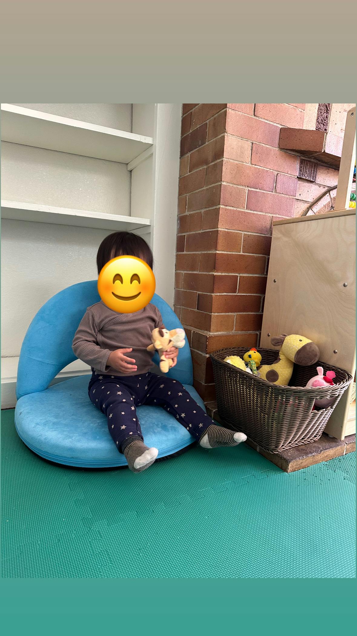 Child sitting on a blue chair holding a small toy