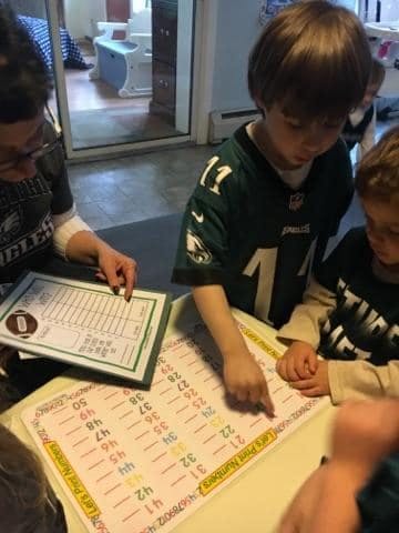 Person and child pointing at numbers on a learning chart