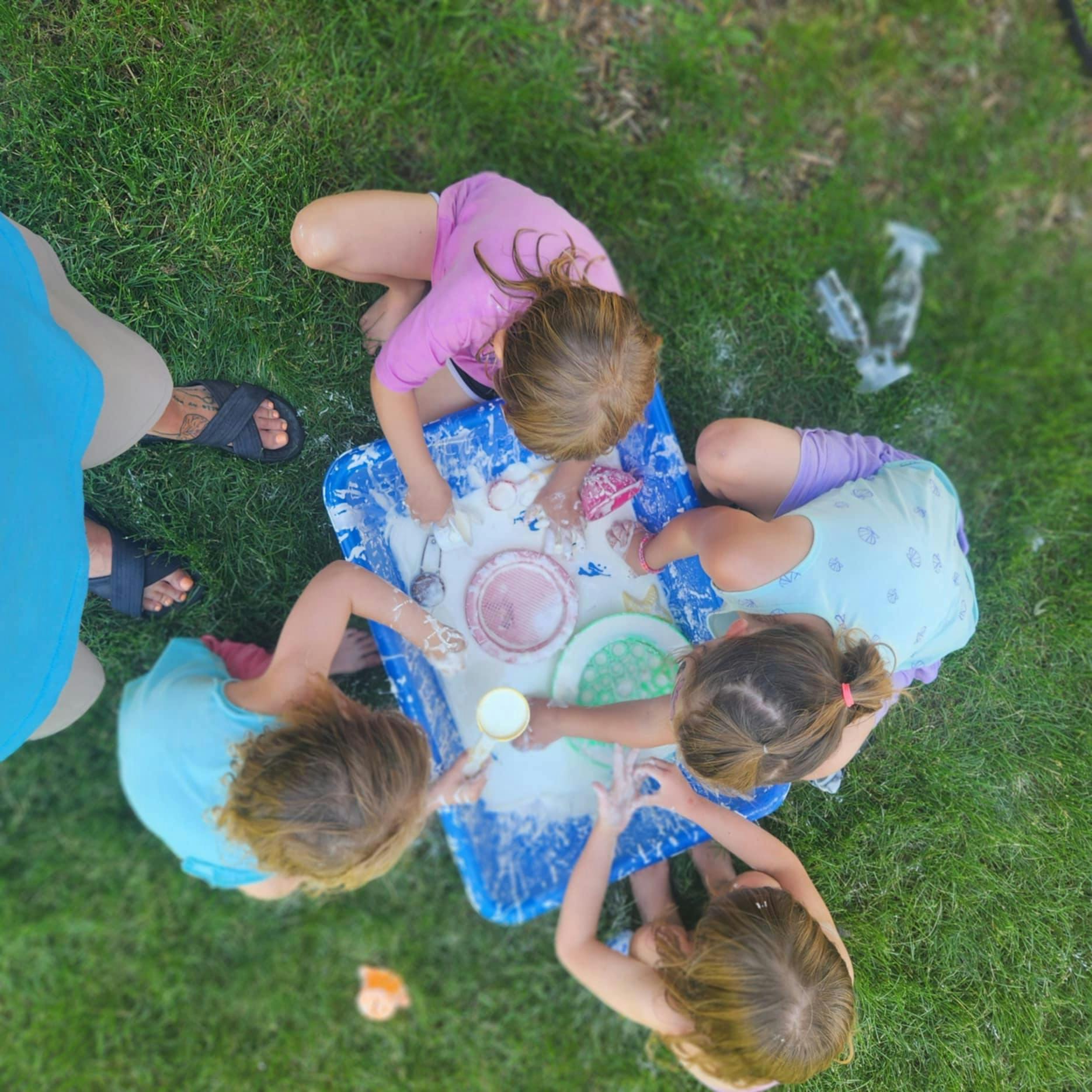 Children playing with a water table on grass