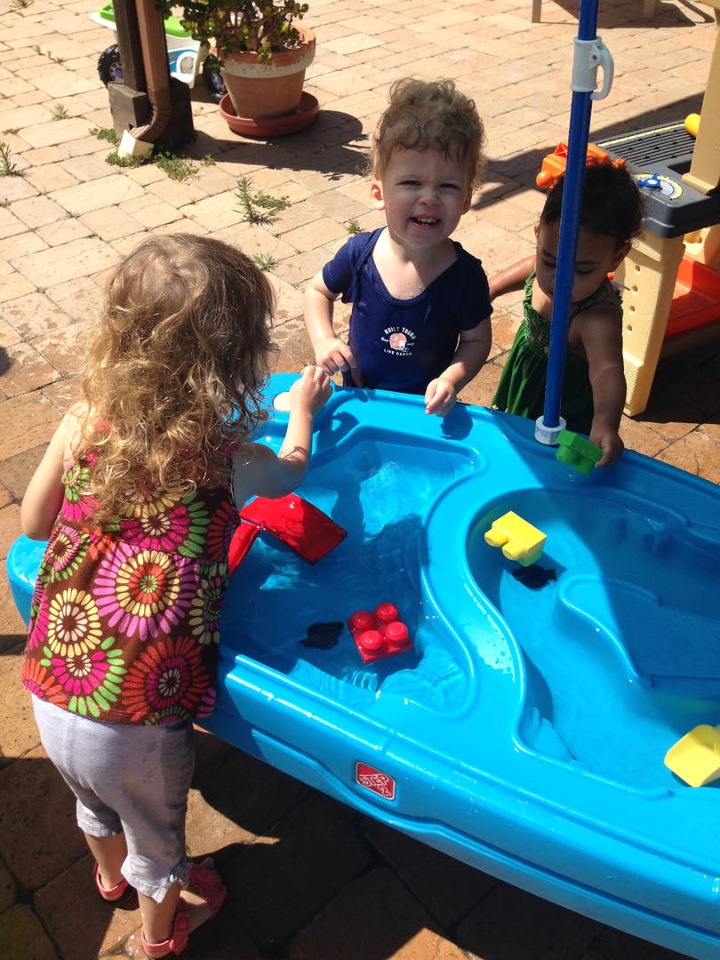 Three children playing with a water table