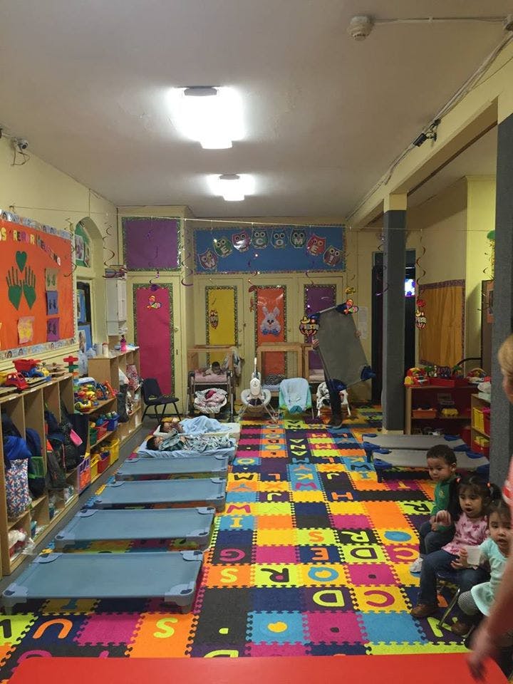 Classroom with colorful alphabet floor mats, cots, and children